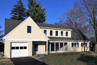 Modelo de fachada de casa beige de estilo americano de tamaño medio de dos plantas con revestimientos combinados, tejado a dos aguas y tejado de teja de madera