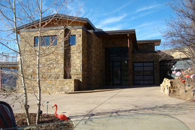 Example of a large mountain style brown two-story stone house exterior design in Denver