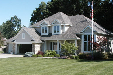 Mid-sized elegant gray two-story stone house exterior photo in Grand Rapids with a hip roof and a shingle roof