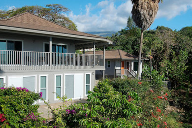 Diseño de fachada de casa gris tropical grande de dos plantas con revestimiento de estuco, tejado a cuatro aguas y tejado de teja de madera