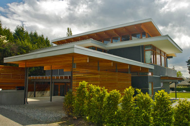 Exemple d'une grande façade de maison grise tendance en verre à un étage avec un toit plat.