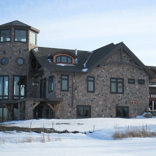 Example of a large trendy brown three-story stone gable roof design in Other