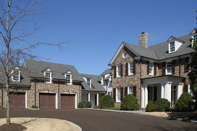 Large elegant brown two-story stone exterior home photo in Other with a shingle roof