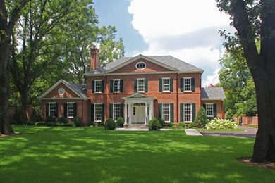 Example of a large classic red two-story brick house exterior design in Other with a hip roof and a shingle roof