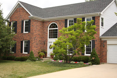 Immagine della facciata di una casa rossa a due piani di medie dimensioni con rivestimento in mattoni