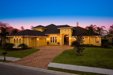 Inspiration for a large mediterranean yellow two-story stucco exterior home remodel in Tampa