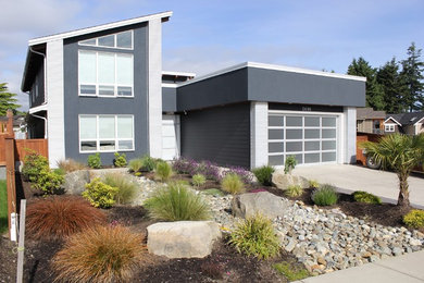 Imagen de fachada de casa gris moderna de tamaño medio de dos plantas con revestimiento de vinilo y tejado de un solo tendido