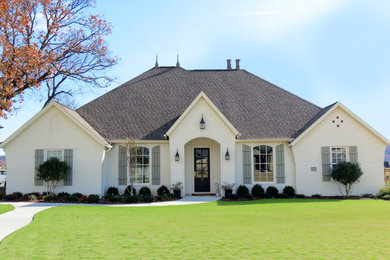 Modelo de fachada de casa beige de estilo americano grande de una planta con revestimiento de estuco, tejado a cuatro aguas y tejado de teja de madera