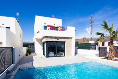 Diseño de fachada blanca mediterránea de dos plantas con revestimiento de aglomerado de cemento