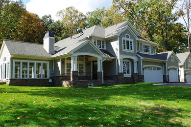 Aménagement d'une grande façade de maison grise craftsman en bois à un étage avec un toit à deux pans.