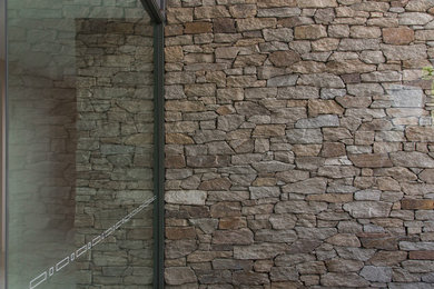 Ejemplo de fachada contemporánea de dos plantas con revestimiento de piedra