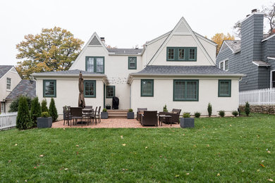 Imagen de fachada de casa blanca clásica de tamaño medio de dos plantas con tejado a dos aguas, revestimiento de estuco y tejado de teja de madera