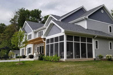 Imagen de fachada de casa gris clásica renovada grande de dos plantas con revestimientos combinados y tejado de teja de madera