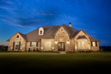 Example of a large classic beige two-story stone exterior home design in Dallas with a shingle roof