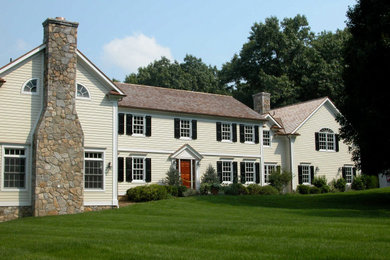 Modelo de fachada de casa beige clásica de tamaño medio de dos plantas con revestimiento de madera, tejado a dos aguas y tejado de teja de madera