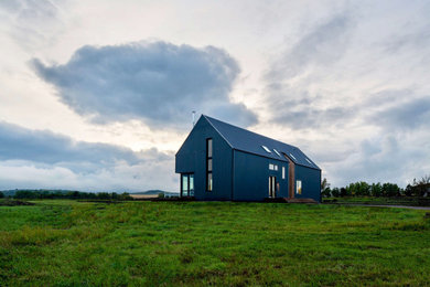 Diseño de fachada de casa negra de estilo de casa de campo de dos plantas con revestimientos combinados, tejado a dos aguas y tejado de metal