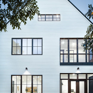 Lantlig inredning av ett stort vitt hus, med två våningar, sadeltak och tak i mixade material