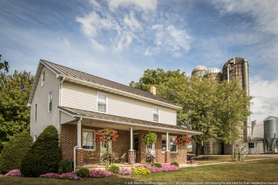 Imagen de fachada de casa beige de estilo de casa de campo de tamaño medio de dos plantas con revestimientos combinados, tejado a dos aguas y tejado de metal