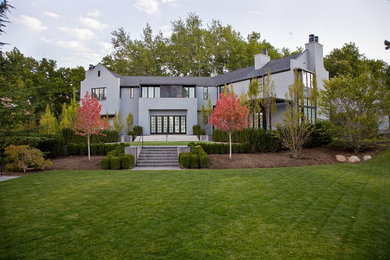Imagen de fachada de casa gris moderna grande de dos plantas con revestimiento de estuco, tejado a dos aguas y tejado de teja de madera