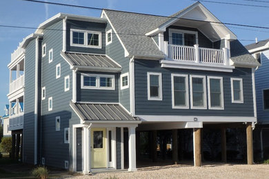 Example of a large beach style gray three-story concrete fiberboard gable roof design in Other