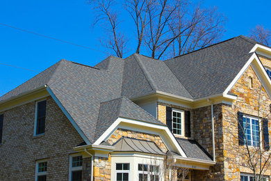 Large elegant brown three-story stone house exterior photo in DC Metro with a clipped gable roof and a shingle roof