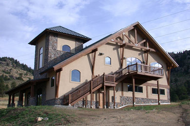 Foto della villa grande marrone rustica a tre piani con rivestimenti misti, tetto a padiglione e copertura in metallo o lamiera