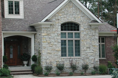 Imagen de fachada beige de estilo americano de dos plantas con revestimiento de piedra