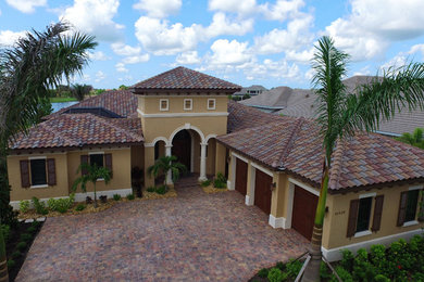Example of a large tuscan beige one-story stucco exterior home design in Tampa with a hip roof