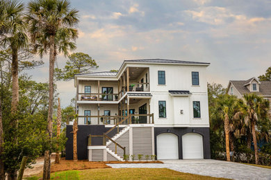 Example of a large beach style white three-story house exterior design in Charleston with a metal roof and a hip roof