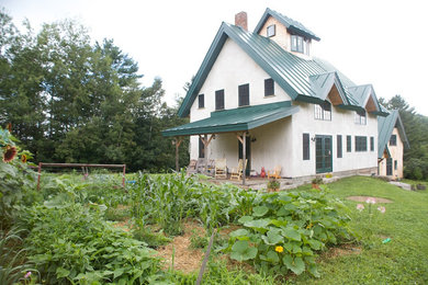 Large farmhouse white three-story stucco gable roof photo in Burlington