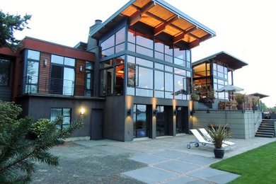 Diseño de fachada de casa multicolor y gris moderna grande a niveles con revestimientos combinados, tejado de un solo tendido y tejado de metal