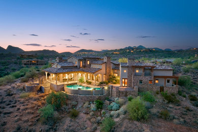 Inspiration for a huge country white two-story stone exterior home remodel in Phoenix with a hip roof
