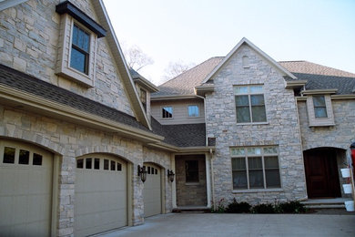 Large traditional beige two-story stone exterior home idea in Other