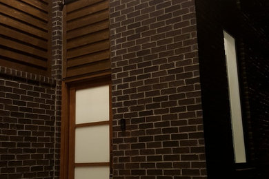 Ejemplo de fachada marrón minimalista de tamaño medio de dos plantas con revestimientos combinados y tejado plano