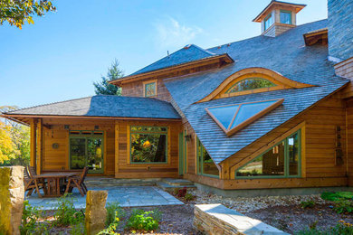 Cette photo montre une grande façade de maison marron montagne en bois à un étage avec un toit à quatre pans.