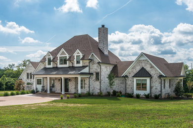 Large cottage white two-story brick house exterior photo in Nashville with a shingle roof and a hip roof