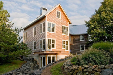 Cette image montre une façade de maison marron rustique en bois de taille moyenne et à deux étages et plus avec un toit à deux pans et un toit en métal.