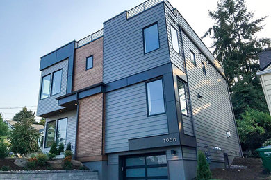Cette photo montre une grande façade de maison multicolore tendance en bois à un étage avec un toit plat et un toit en métal.