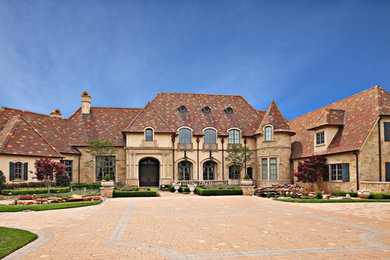 Example of a huge classic beige two-story stucco house exterior design in Dallas with a tile roof