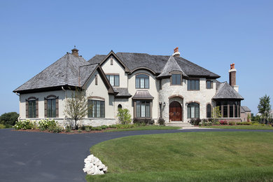Ejemplo de fachada de casa beige contemporánea grande de dos plantas con revestimiento de estuco, tejado a cuatro aguas y tejado de varios materiales