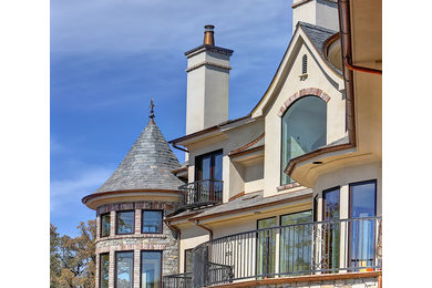 На фото: трехэтажный, серый дом с облицовкой из цементной штукатурки