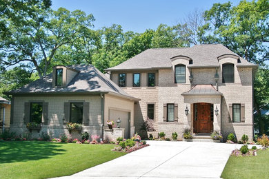 Cette photo montre une grande façade de maison beige à un étage avec un revêtement mixte, un toit à quatre pans et un toit en shingle.