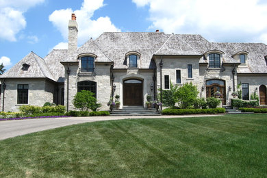 Diseño de fachada de casa gris clásica extra grande de dos plantas con revestimiento de piedra, tejado a cuatro aguas y tejado de teja de madera