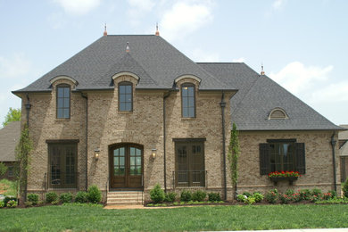 Esempio della facciata di una casa grande marrone eclettica a due piani con rivestimento in mattoni