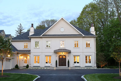 Imagen de fachada de casa beige clásica grande de tres plantas con revestimiento de estuco, tejado a cuatro aguas y tejado de teja de madera