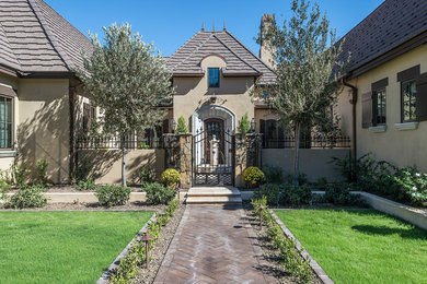 Inspiration pour une façade de maison beige traditionnelle en stuc de taille moyenne et de plain-pied avec un toit à quatre pans.