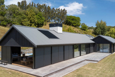Diseño de fachada de casa negra marinera grande de una planta con revestimientos combinados y tejado de metal
