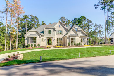 Large transitional beige three-story brick house exterior photo in Raleigh with a hip roof and a mixed material roof