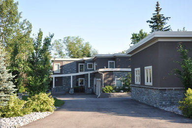 Example of a large transitional gray two-story stucco flat roof design in Calgary