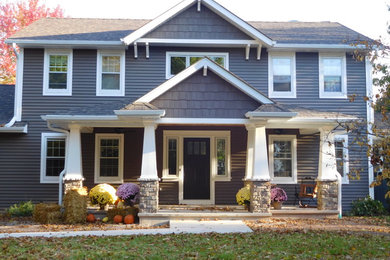 Modelo de fachada de casa azul de estilo americano de tamaño medio de dos plantas con revestimiento de vinilo, tejado a dos aguas y tejado de teja de madera
